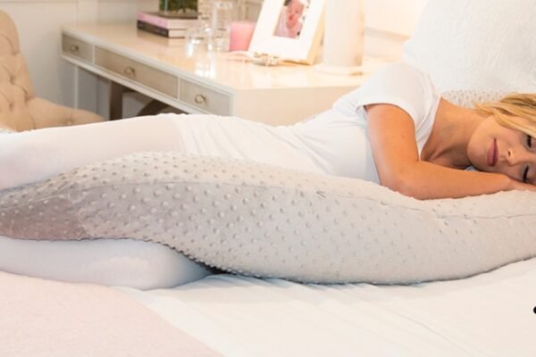 A pregnant woman comfortably resting with a U-shaped pregnancy pillow for full-body support and better sleep.